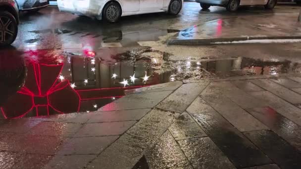 View of cars standing in a traffic jam and a puddle in which the Christmas illumination is reflected. — Stock Video