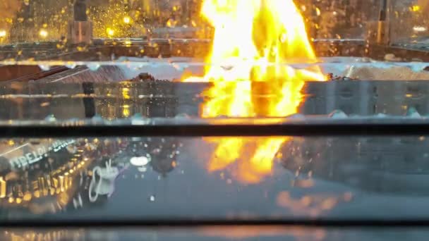 Blick auf die Flamme des Feuers durch das Schutzglas, das auf der Straße entzündet wird, um Passanten im Café zu erwärmen. — Stockvideo