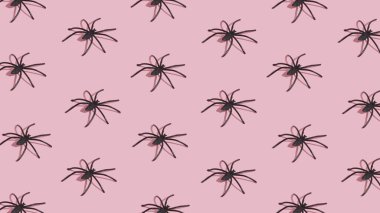 Pembe arka planda siyah örümceklerden oluşan Cadılar Bayramı deseni. En az Cadılar Bayramı konsepti.