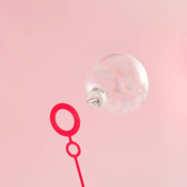 Şeffaf Noel mücevheri ve pembe arka planda kırmızı balon üreticisi yaratıcı bir fikir. Asgari Yeni Yıl kavramı.