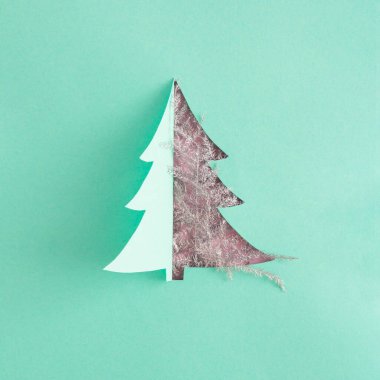 Pembe arka planda dallarla kesilmiş yeşil kağıttan yapılmış yaratıcı minimal Noel ağacı. Yeni Yıl Estetik Kompozisyonu.