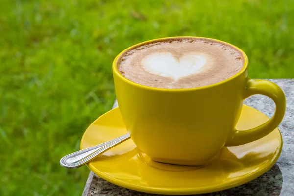 Uma xícara de café com padrão cardíaco em uma xícara amarela . — Fotografia de Stock