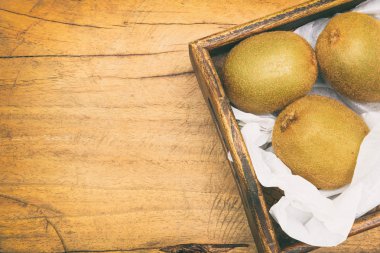 Ahşap arka plan kopya alanı ile bir tepsi içinde kivi. Tonda 