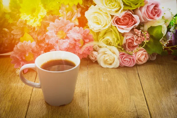 Taza de café sobre una mesa de madera con fondo de flores debajo de mor —  Fotos de Stock
