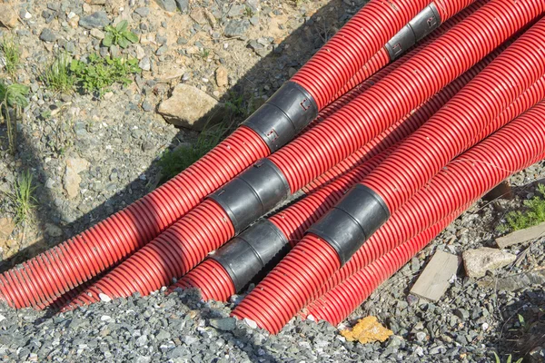 Tubos ondulados vermelho com conectores pretos fora do solo no th — Fotografia de Stock