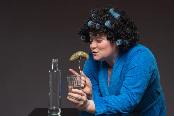 Eenzame vrouw is drinken uit een tumbler glazen wodka en eatin — Stockfoto