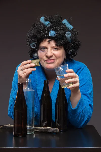 Lonely middle-aged woman drinking beer and vodka and eating pick — Stock Photo, Image