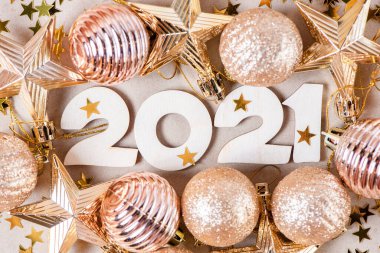 Parlak altın Noel topları ve parıldayan yıldızlarla dolu bir arka planda 2021 numaralı tahta. Güzel yeni yıl kartı.