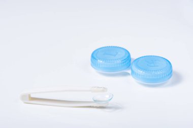 Beyaz zemin üzerinde çözeltiye yakın kontak lensleri, konteynır ve cımbızla metin için yer. Makro fotoğrafçılık