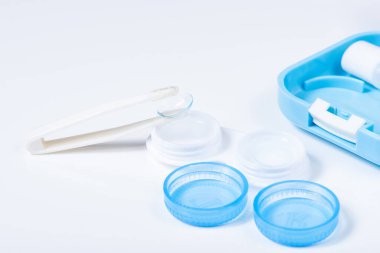 Beyaz zemin üzerinde çözeltiye yakın kontak lensleri, konteynır ve cımbızla metin için yer. Makro fotoğrafçılık