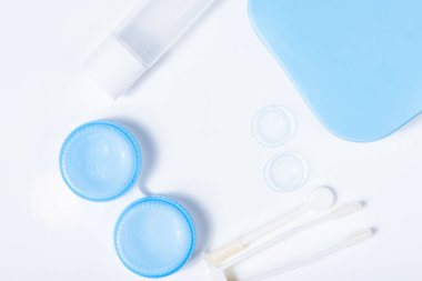 Beyaz zemin üzerinde çözeltiye yakın kontak lensleri, konteynır ve cımbızla metin için yer. Makro fotoğrafçılık