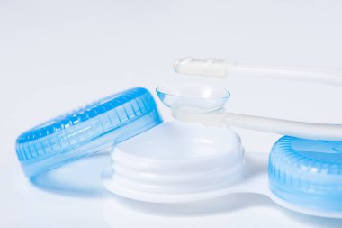 Beyaz zemin üzerinde çözeltiye yakın kontak lensleri, konteynır ve cımbızla metin için yer. Makro fotoğrafçılık