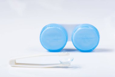 Beyaz zemin üzerinde çözeltiye yakın kontak lensleri, konteynır ve cımbızla metin için yer. Makro fotoğrafçılık