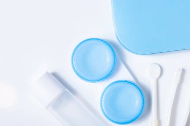 Beyaz zemin üzerinde çözeltiye yakın kontak lensleri, konteynır ve cımbızla metin için yer. Makro fotoğrafçılık