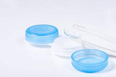 Beyaz zemin üzerinde çözeltiye yakın kontak lensleri, konteynır ve cımbızla metin için yer. Makro fotoğrafçılık