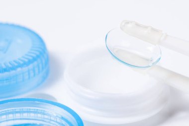 Beyaz zemin üzerinde çözeltiye yakın kontak lensleri, konteynır ve cımbızla metin için yer. Makro fotoğrafçılık