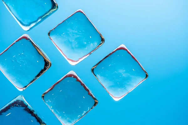 飲み物のための透明な正方形の氷のような立方体が付いているスタイリッシュな青い背景 フラットレイマクロ写真 — ストック写真