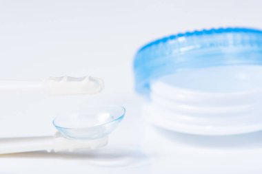 Beyaz zemin üzerinde çözeltiye yakın kontak lensleri, konteynır ve cımbızla metin için yer. Makro fotoğrafçılık