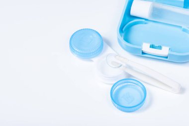 Beyaz zemin üzerinde çözeltiye yakın kontak lensleri, konteynır ve cımbızla metin için yer. Makro fotoğrafçılık