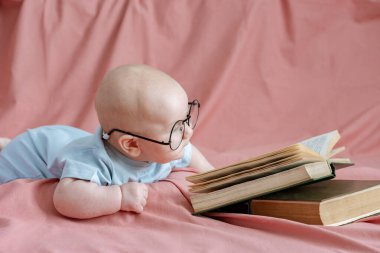 Şirin, güzel, akıllı bir bebek evdeki yatağın üzerinde bir kitabın yanında yatıyor. Çocuk eğitimi 