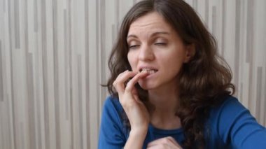 Kıvırcık saçlı, sivilceli güzel bir kız. Düşünüyor ve tırnaklarını yiyor. 