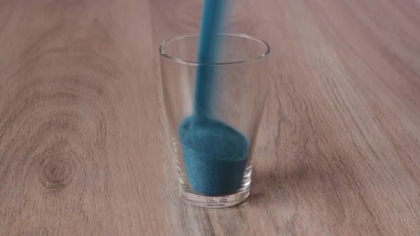 Barevný písek se nalije do skleněného a mušlí umístěných nahoře — Stock video