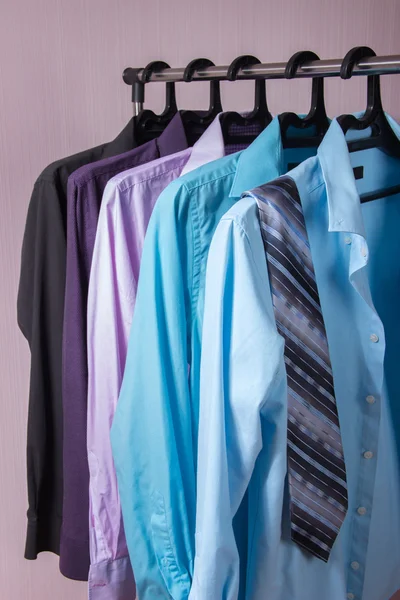 Цветные мужские рубашки, которые висят на вешалках — стоковое фото