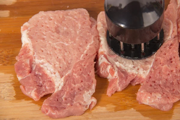 Beat the meat on a wooden board on a white background — Stock Photo, Image