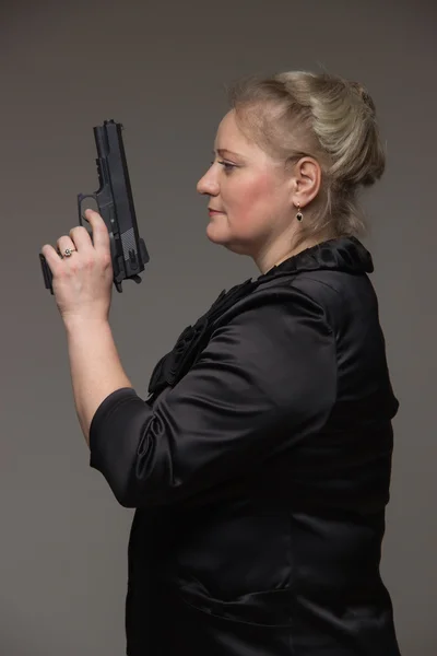 Een vrouw in een zwarte jas met een zwarte pistool — Stockfoto