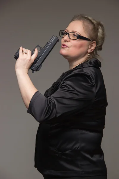 Een vrouw in een zwarte jas met een zwarte pistool — Stockfoto
