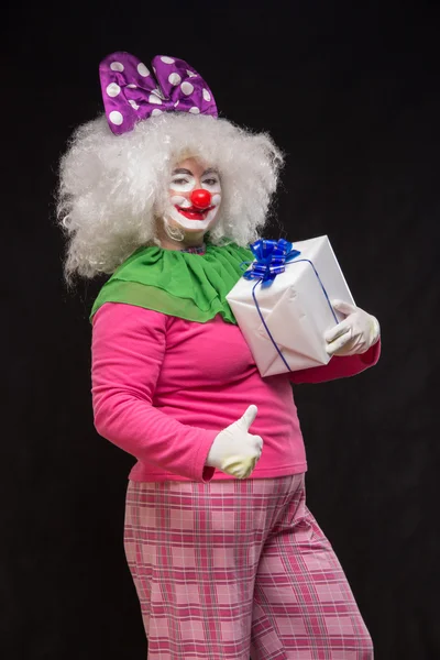 Funny clown with shaggy hair and a cheerful make-up holding a gi — Stock Photo, Image