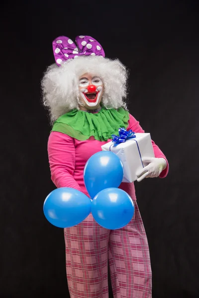 Funny clown with shaggy hair and a cheerful make-up holding a gi — Stock Photo, Image
