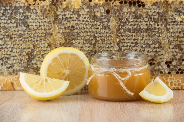 Goldener Honig in der Wabe in einem Glas und gelbe Zitronenscheiben — Stockfoto