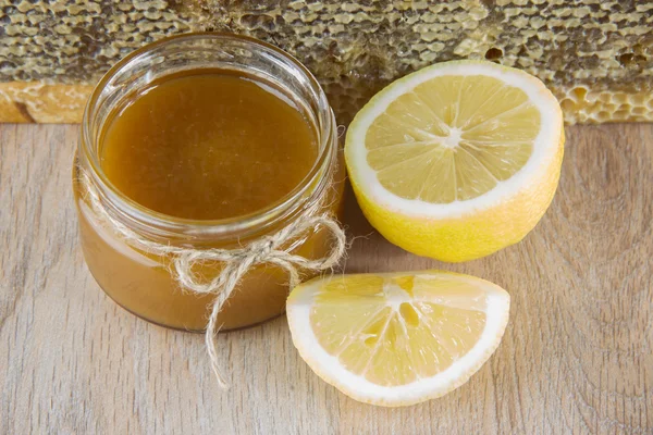 Golden honey i kammen i en burk och gul skivad citron — Stockfoto