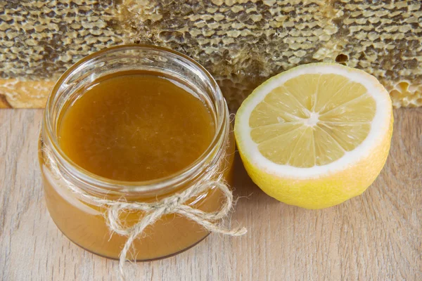 Золотой мед в расческе в банке и желтый нарезанный лимон — стоковое фото