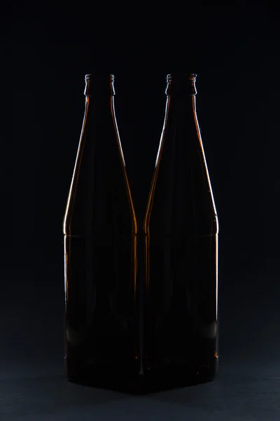 Silhouettes brown glass bottles for beer on a black background — Stock Photo, Image