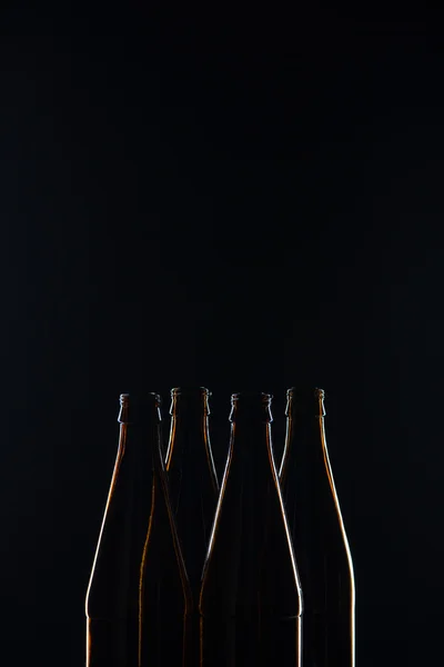 Σιλουέτες καφέ γυάλινες φιάλες για μπύρα σε μαύρο φόντο — Φωτογραφία Αρχείου