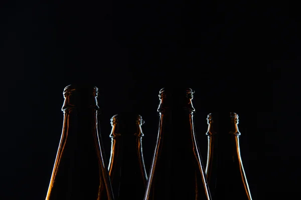 Garrafas de vidro marrom silhuetas para cerveja em um fundo preto — Fotografia de Stock