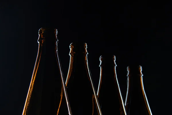 Garrafas de vidro marrom silhuetas para cerveja em um fundo preto — Fotografia de Stock