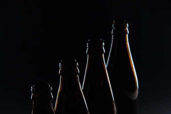 Silhouettes brown glass bottles for beer on a black background