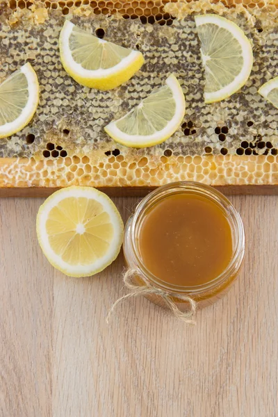 Goldener Honig in der Wabe in einem Glas und gelbe Zitronenscheiben — Stockfoto