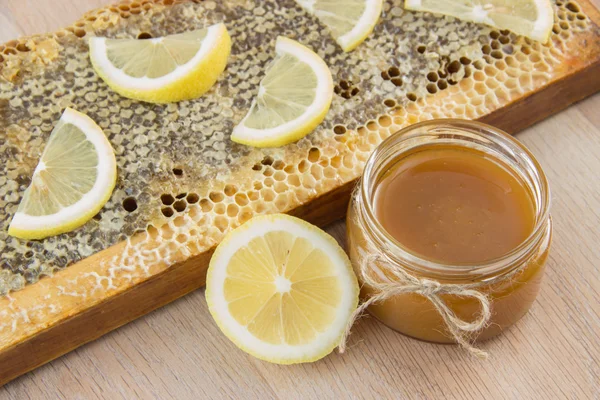 Miel dorada en el peine en un frasco y limón en rodajas amarillas — Foto de Stock