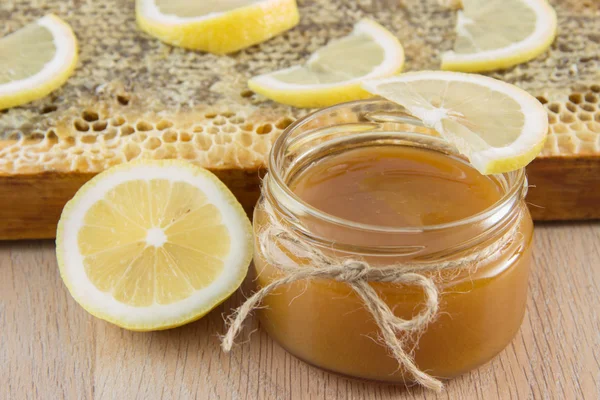 Miel dorada en el peine en un frasco y limón en rodajas amarillas —  Fotos de Stock