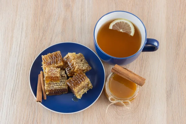 Goldwabenstücke auf einem Tisch mit Tee, Zitrone und Zimt — Stockfoto
