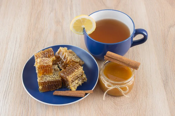 Stukken van gouden honing kam op een tabel met thee, citroen en cinna — Stockfoto