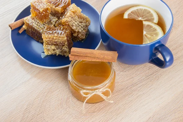 Trozos de peine de miel dorada sobre una mesa con té, limón y cinna —  Fotos de Stock