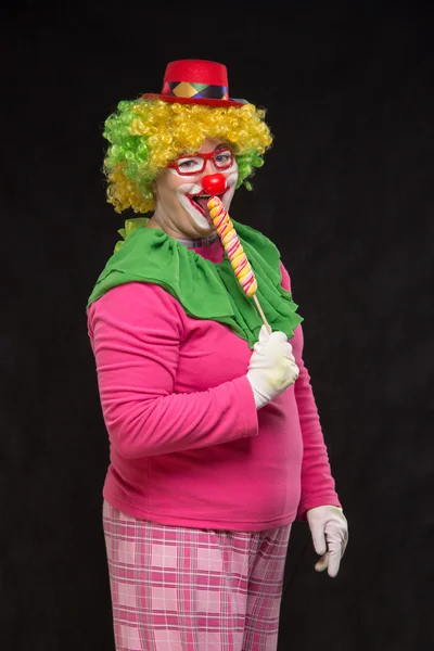 Cheerful funny clown in a hat with a big candy — Stock Photo, Image