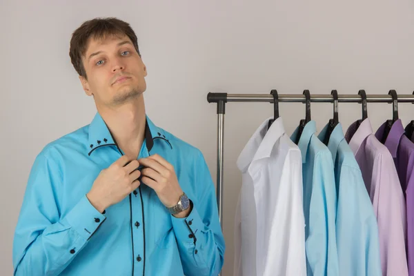 Joven sexy hombre elige una camisa de una variedad de camisas colgando —  Fotos de Stock