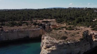 Güney Avrupa 'da güzel bir uçurum kıyısı manzarası. Mavi gökyüzü ve berrak suyla güneşli bir günde Portekiz 'deki Benagil mağaralarını gösteriyor..