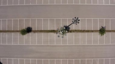 Güneşli bir günde havadan çekilmiş boş bir otopark görüntüsü. Asfalt ve beyaz çizgili araba alanları drone görüntüsü..